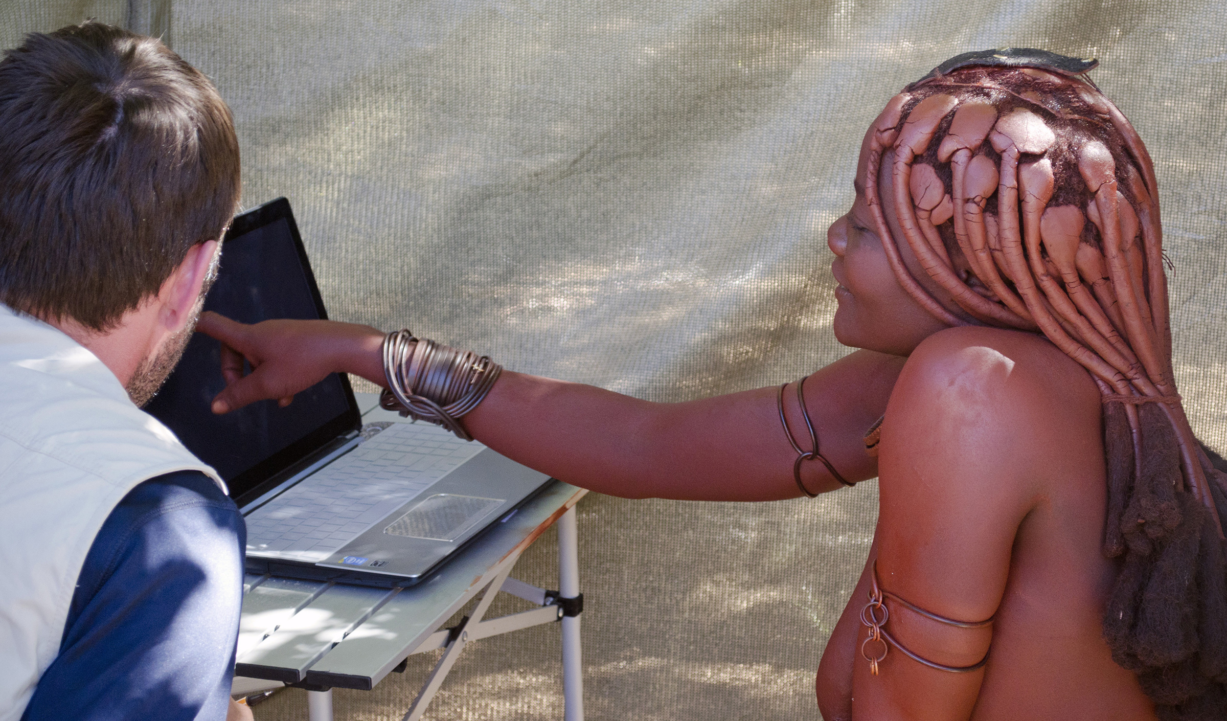 University of Utah anthropologist Layne Vashro with a woman from the Twe tribe in Namibia as she performs a mental rotation task on a laptop computer. It was part of a new study  that found evidence men evolved better navigation ability than women because men with better ability to manipulate objects in their mind can roam farther and have children with more mates.