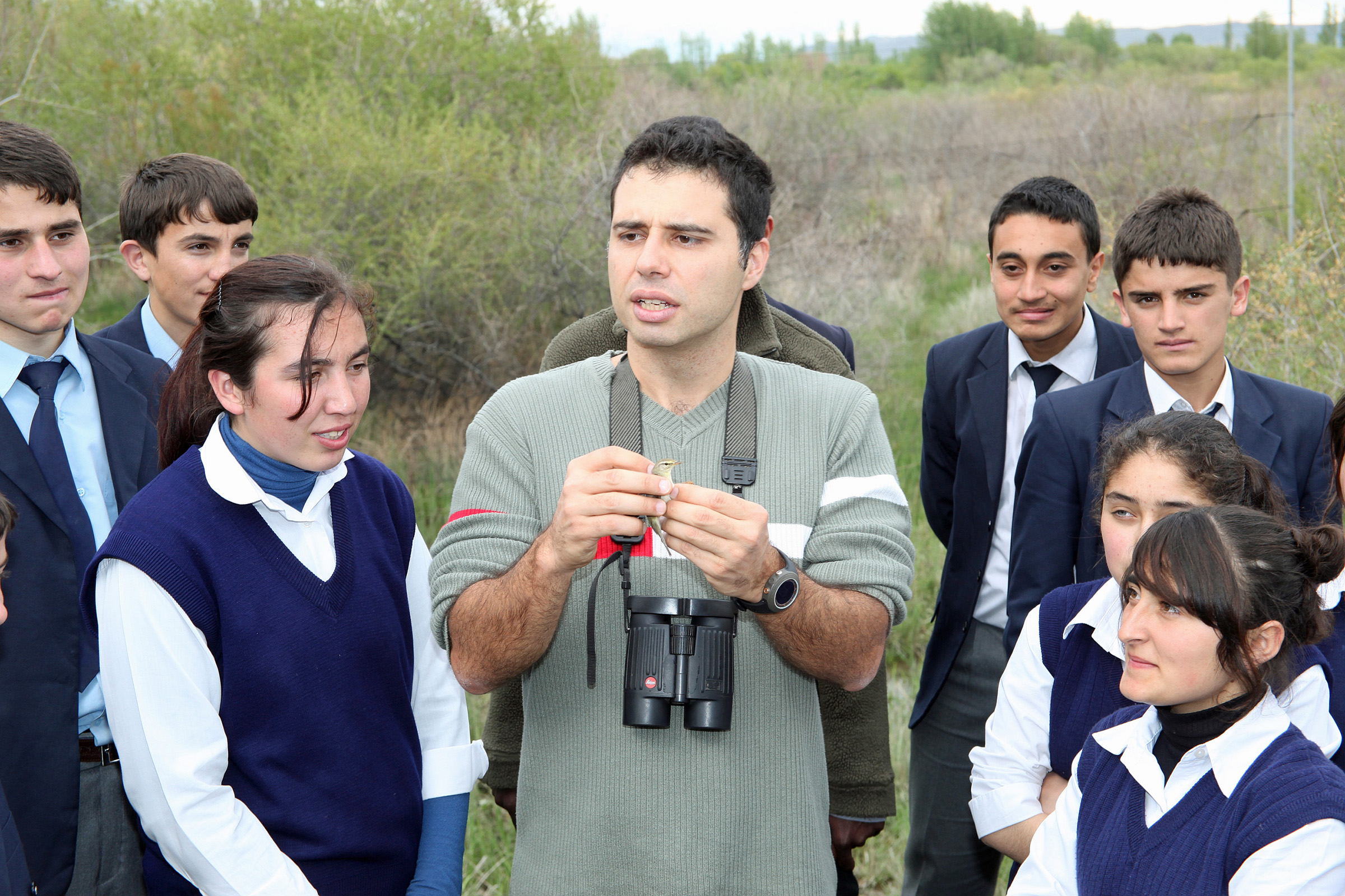 University of Utah biologist Çağan Şekercioğlu holds a willow warbler as he talks with Turkish students at eastern Turkey’s bird-rich Aras River wetlands, which are threatened by dam construction. Şekercioğlu has won Turkey’s highest scientific honor.
