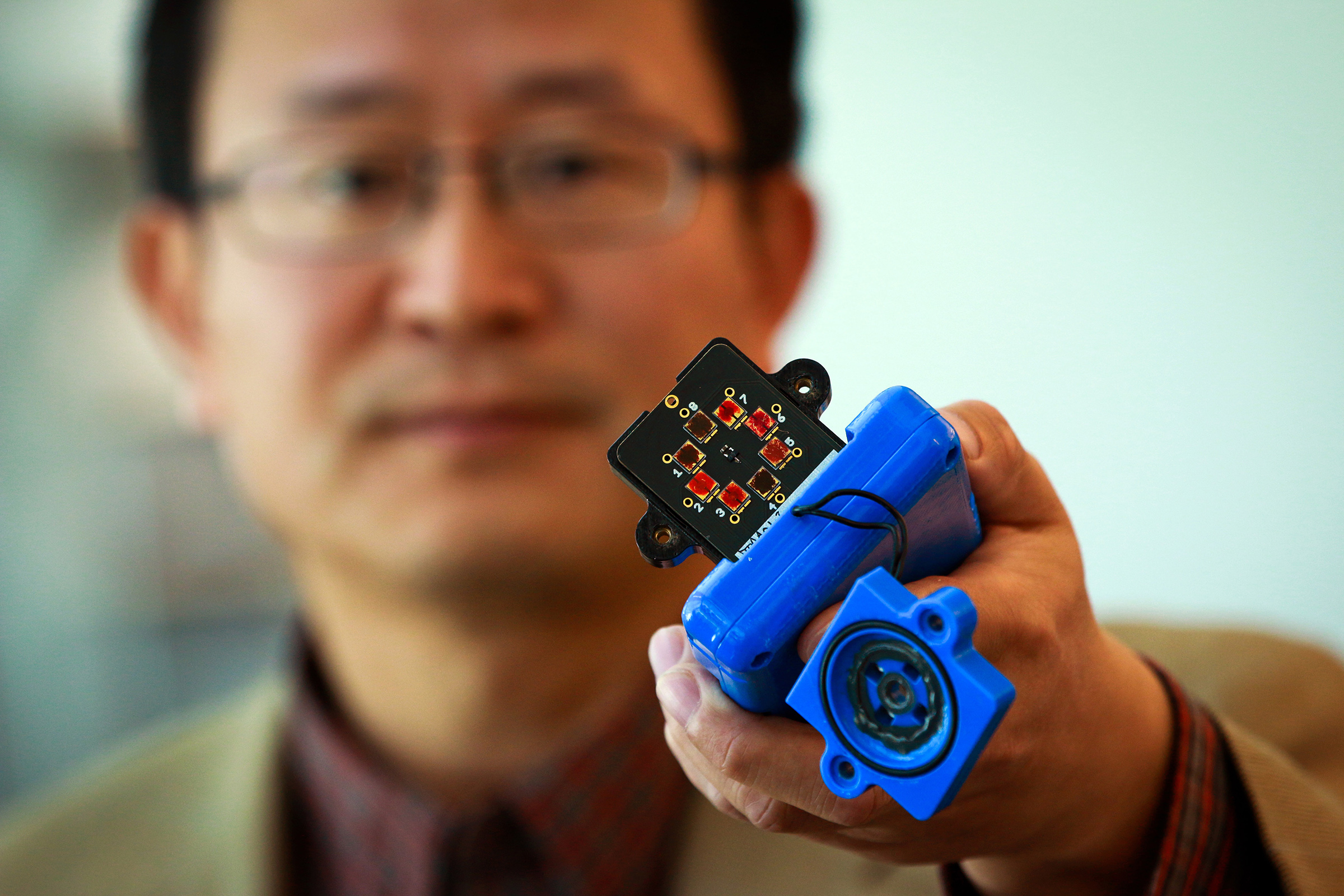 Ling Zang, a University of Utah professor of materials science and engineering, holds a prototype detector that uses a new type of carbon nanotube material for use in handheld scanners to detect explosives, toxic chemicals and illegal drugs. Zang and colleagues developed the new material, which will make such scanners quicker and more sensitive than today’s standard detection devices. Ling’s spinoff company, Vaporsens, plans to produce commercial versions of the new kind of scanner early next year.