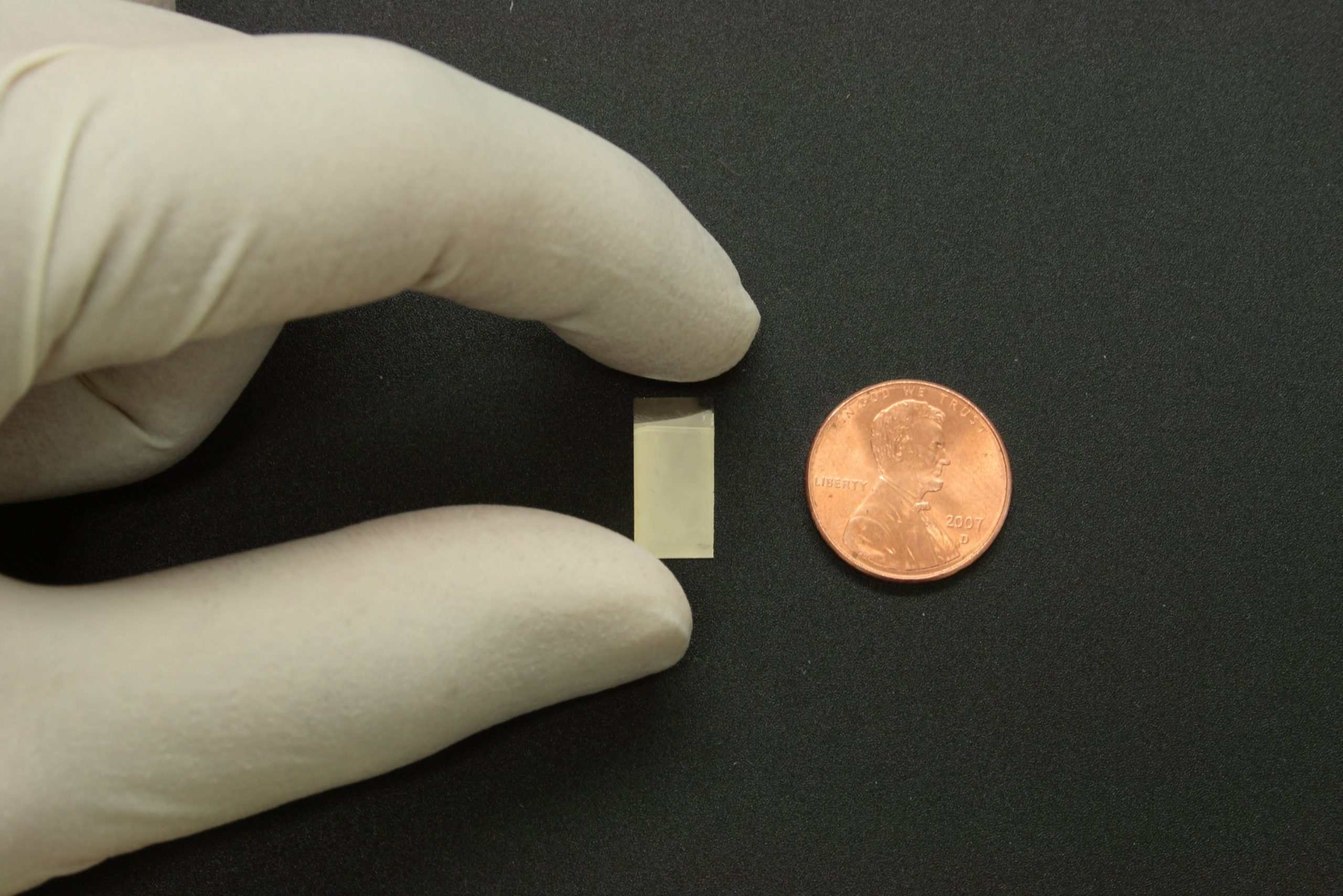 A silver nanoparticle mirror is held next to a U.S. penny for scale. University of Utah physicists and chemists developed a new microscope method for looking at the internal structure of certain biological materials using "hotspots" of bright white light generated when the silver nanoparticles are hit with infrared laser light. The method also could be used to routinely check the integrity of a new generation of aircraft with fuselages, wings and tails made of carbon fiber.